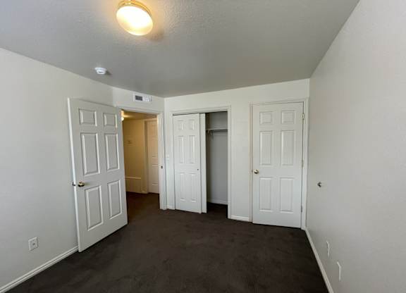 A room with white doors and carpeted floor.