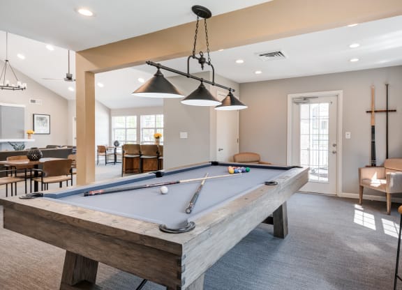 a pool table in the clubhouse of a home with a living room and dining area