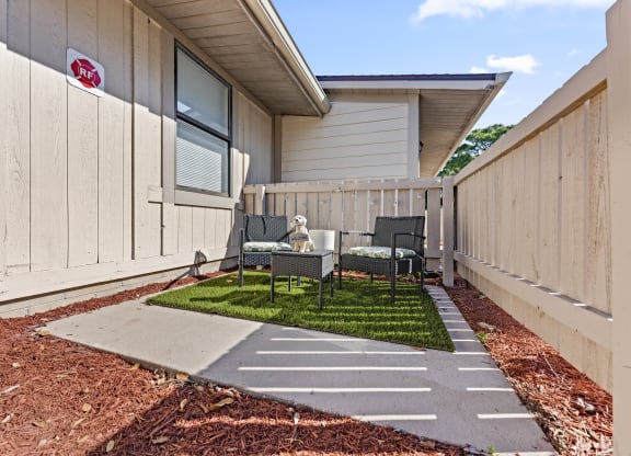 a patio with a table and chairs in front of a house