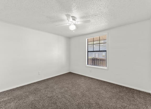 an empty living room with a ceiling fan and a window