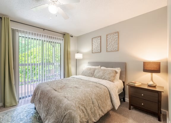 a bedroom with a bed and a sliding glass door to a balcony