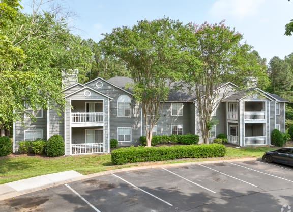 an apartment building with a parking lot and trees