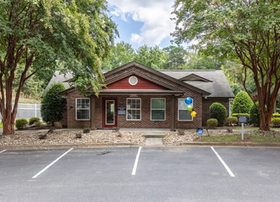 a small brick house in a parking lot with trees