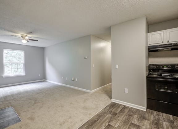 an empty living room and kitchen with a ceiling fan