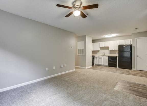 an empty living room and kitchen with a ceiling fan