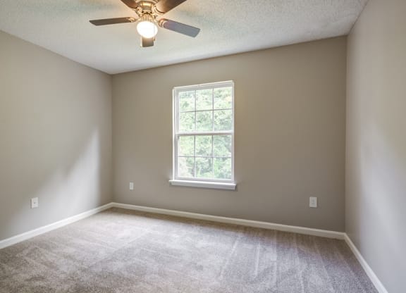 an empty room with a ceiling fan and a window