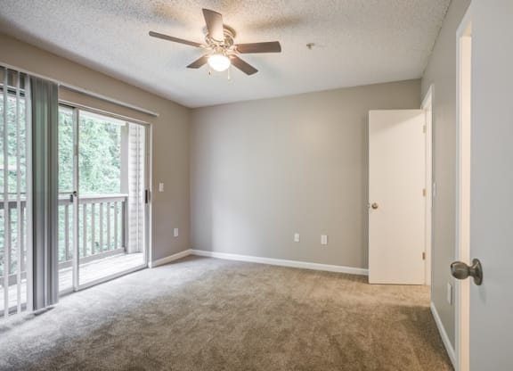 an empty living room with a ceiling fan and a window