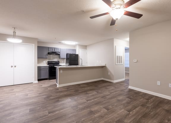 an empty living room and kitchen with a ceiling fan