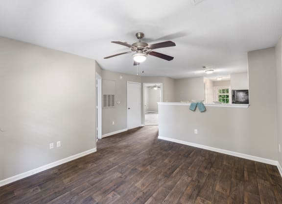 an empty living room and kitchen with a ceiling fan