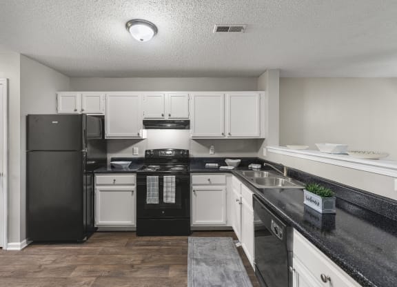 an empty kitchen with black appliances and white cabinets