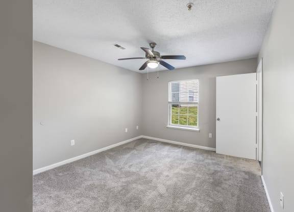 an empty room with a ceiling fan and a window