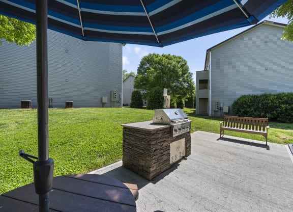 a patio with an outdoor grill and a table with an umbrella