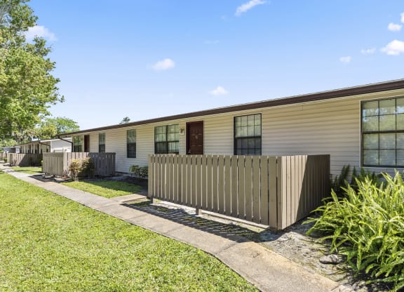 the exterior of a yellow house with a fence and grass