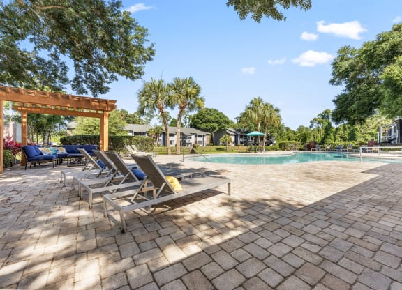 a swimming pool with chaise lounge chairs and trees