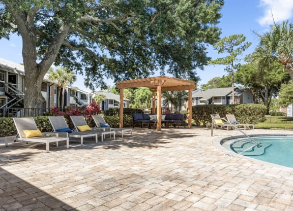 a backyard with a pool and patio with chairs and a gazebo