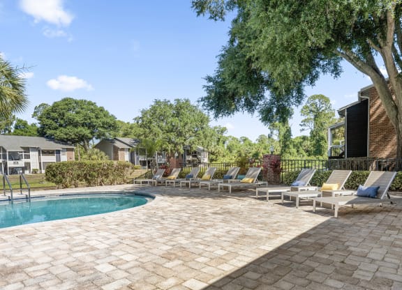 a swimming pool with chaise lounge chairs next to a house
