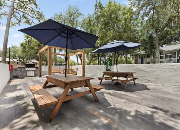 two picnic tables with umbrellas on a patio