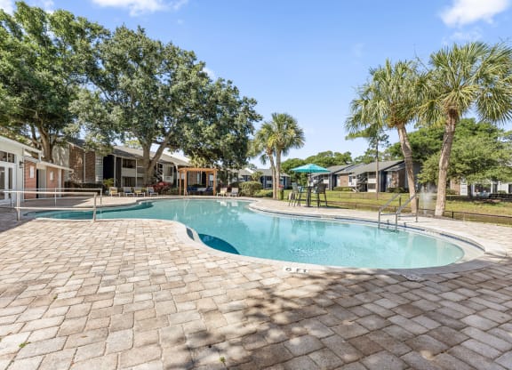 a resort style swimming pool with trees and buildings in the background