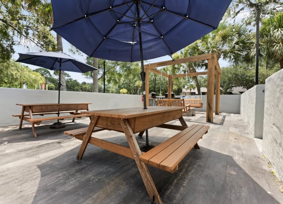 a picnic table with umbrellas and benches on a patio