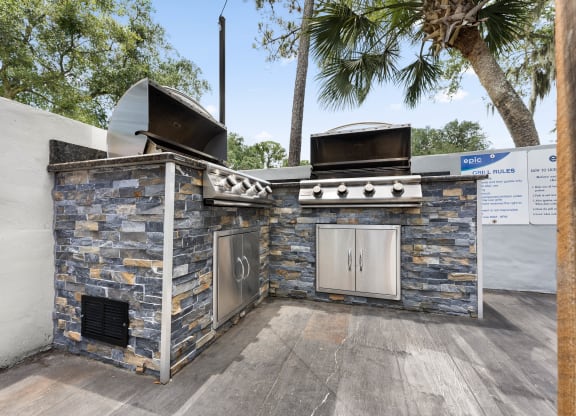 a barbecue grill with a stone wall and two stoves