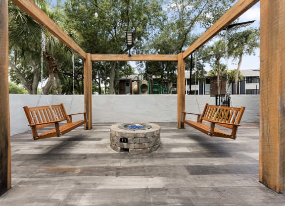 a fire pit in the middle of a patio with benches