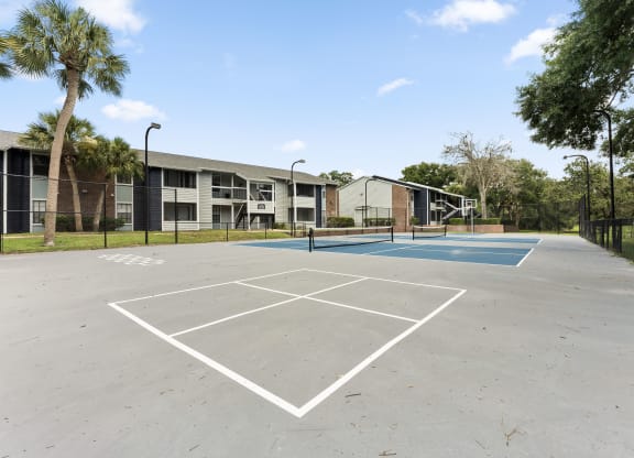 an empty basketball court with apartments in the background