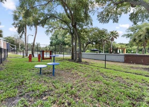 a playground and picnic table in a park with a tennis court