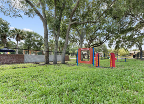 a park with a playground and a fence and trees