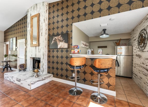 a kitchen with a bar with two stools and a fireplace