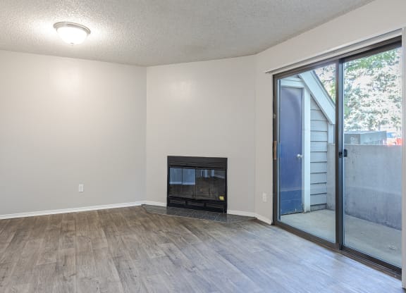 an empty living room with a fireplace and a sliding glass door