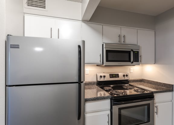 a kitchen with white cabinets and stainless steel appliances and a refrigerator