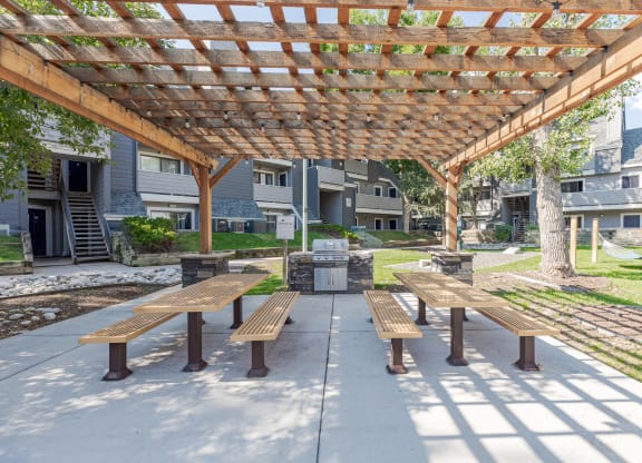 a picnic area with benches under a wooden pergola