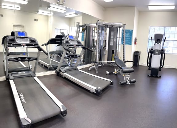 a gym with cardio equipment and weights on the floor