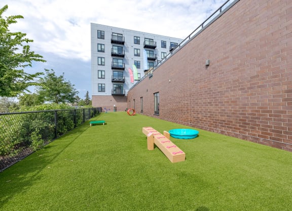 A playground with a green lawn and a brick wall.