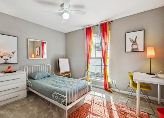 A bedroom with a white bed, a white desk, and a white dresser.