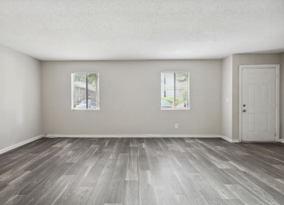 the living room of an empty house with wood floors and a door