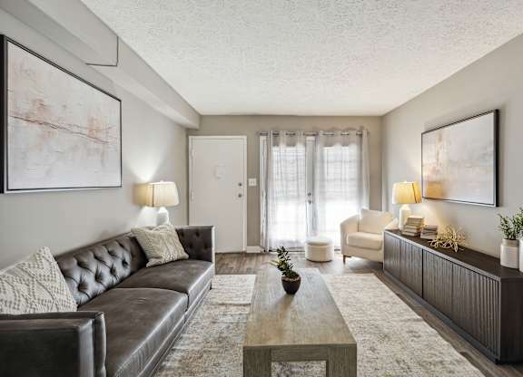 A living room with a brown leather couch and a coffee table in the center.