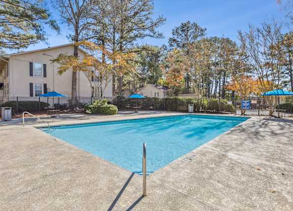 A swimming pool surrounded by a fence and trees.