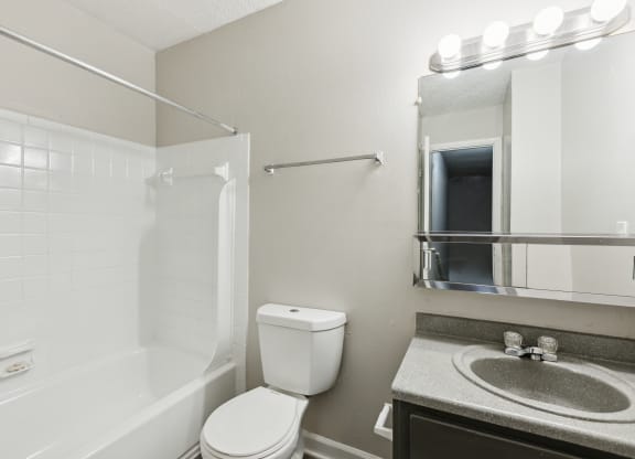 a bathroom with a toilet sink and shower and a mirror