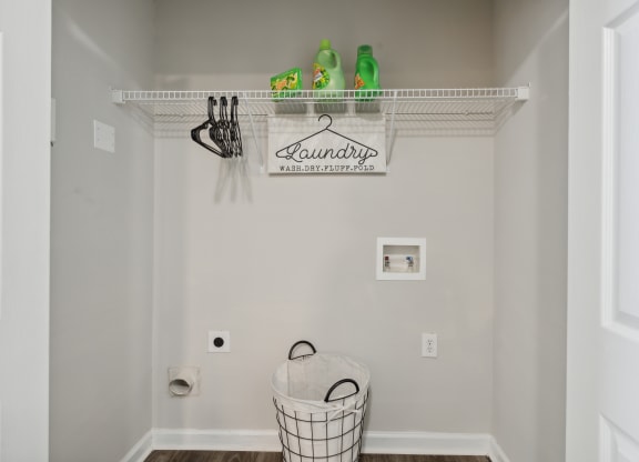 a laundry room with a basket and a sign on the wall and a rack above