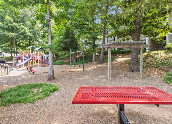 a park with a red picnic table and playground equipment