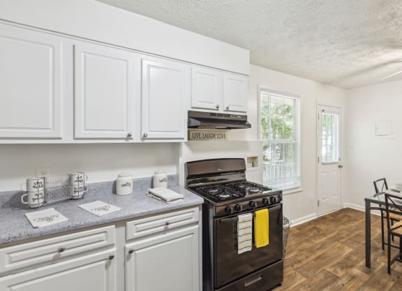 a kitchen with white cabinets and black appliances and a dining room table