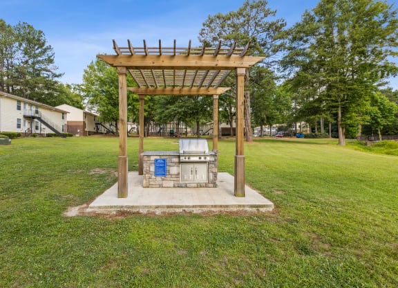 the gazebo with a grill in the middle of the yard