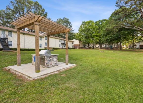 a backyard with a grill and a wooden pergola