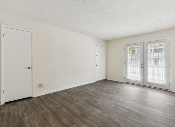 the living room of an apartment with white walls and wood floors