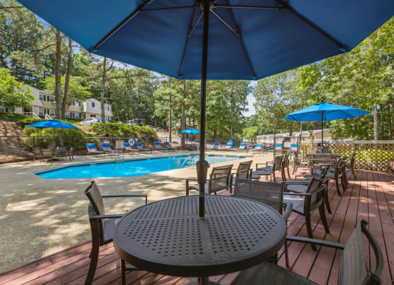 a patio with tables and umbrellas and a swimming pool