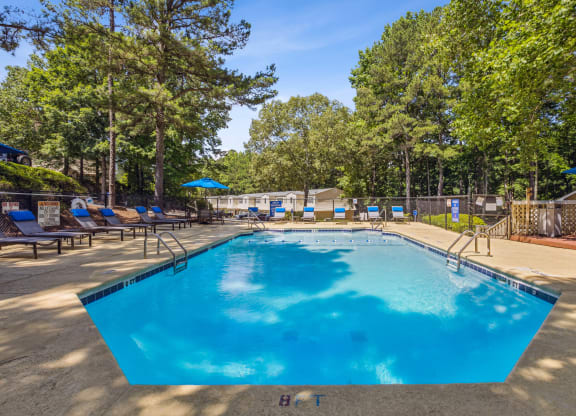 our resort style swimming pool is surrounded by chairs and trees