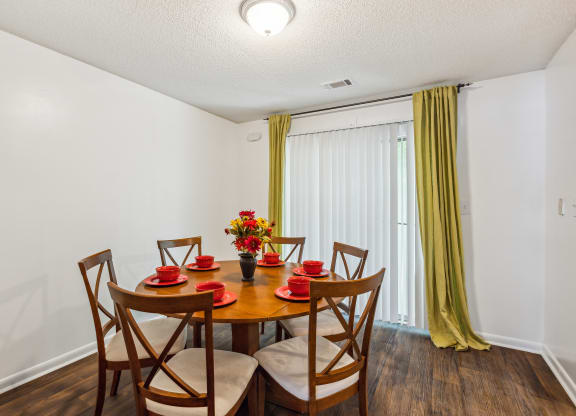 a dining room with a table and chairs and a window with yellow curtains
