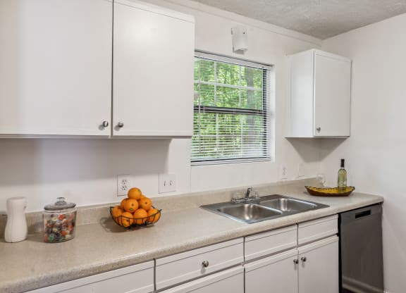 a kitchen with white cabinets and a sink and a window