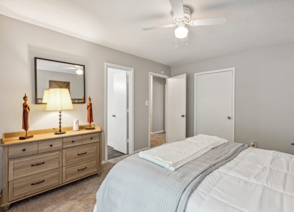 a bedroom with a bed and a dresser and a ceiling fan